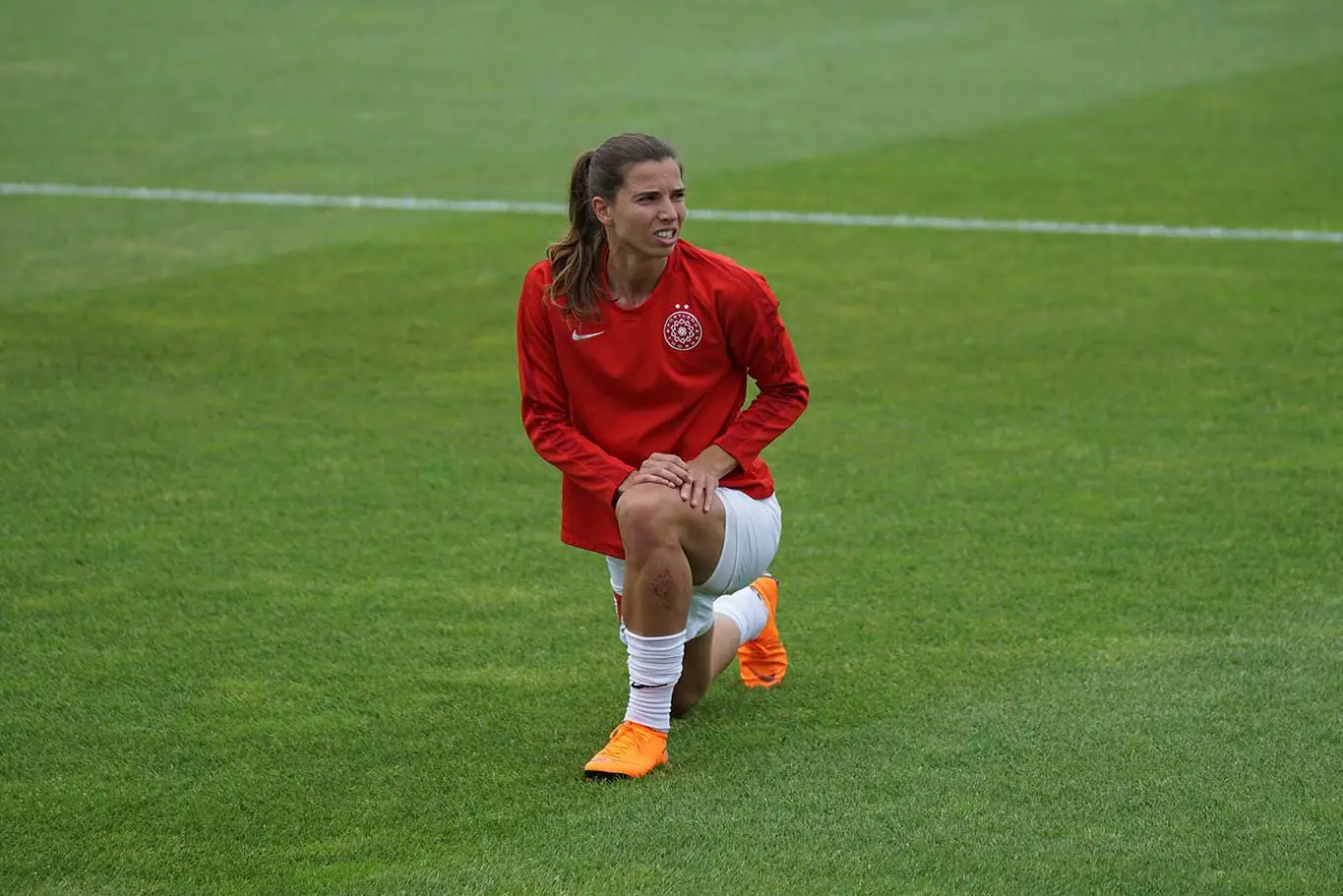 Female athlete stretching leg on field